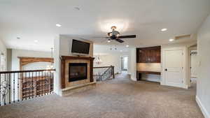 Unfurnished living room featuring light carpet, a chandelier, recessed lighting, a ceiling fan, and built in desk