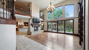 Unfurnished living room featuring a fireplace, a chandelier, recessed lighting, a towering ceiling, and stone tile floors