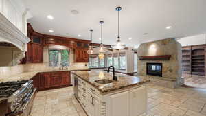 Kitchen featuring glass insert cabinets, stainless steel appliances, dark stone countertops, backsplash, and stone tile flooring