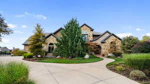 View of front of home featuring stone siding and a front lawn