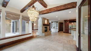 Unfurnished living room featuring a chandelier, stone tile floors, recessed lighting, a fireplace, and arched walkways