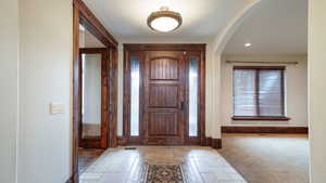 Entrance foyer with arched walkways, recessed lighting, and stone tile flooring