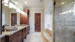 Full bath featuring ornamental molding, double vanity, a bath, a walk in shower, and light tile patterned flooring
