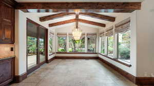 Unfurnished sunroom with stone tile flooring and a chandelier