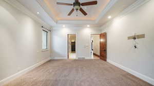 Unfurnished bedroom with carpet floors, a tray ceiling, ornamental molding, a ceiling fan, and recessed lighting