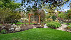 View of grassy yard with view of wooded area