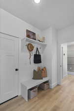 Mudroom featuring light wood-style flooring and baseboards