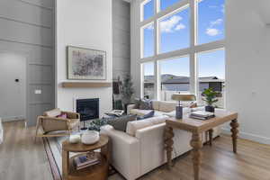 Living room featuring built in features, light wood-type flooring, a glass covered fireplace, and a towering ceiling