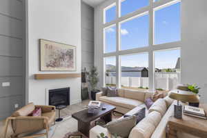 Living area featuring built in features, wood finished floors, healthy amount of natural light, a towering ceiling, and a glass covered fireplace