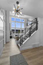 Staircase with wood finished floors and a chandelier
