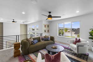 Carpeted living area with ceiling fan and recessed lighting