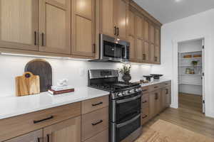Kitchen featuring stainless steel appliances, light stone counters, tasteful backsplash, and light wood-style floors