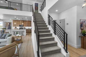 Staircase featuring recessed lighting, wood finished floors, a towering ceiling, and ceiling fan