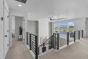 Corridor featuring an upstairs landing, carpet, recessed lighting, and a tray ceiling