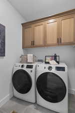 Washroom with tile patterned flooring, cabinet space, and washer and clothes dryer