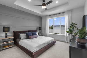 Bedroom with a tray ceiling, light carpet, ceiling fan, and recessed lighting