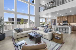 Living area with recessed lighting, light wood-type flooring, a chandelier, and a high ceiling