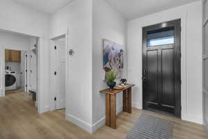 Foyer with light wood-type flooring and washer / dryer