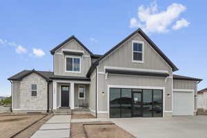 View of front facade with board and batten siding, stone siding, concrete driveway, and covered porch