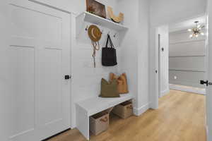 Mudroom with light wood-style flooring and a chandelier