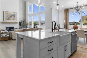 Kitchen featuring open floor plan, a center island with sink, white cabinets, light wood finished floors, and recessed lighting
