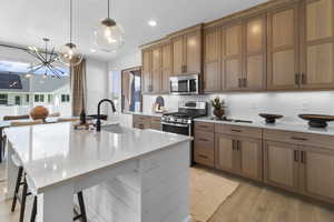 Kitchen with light stone counters, tasteful backsplash, open floor plan, an island with sink, and a kitchen breakfast bar