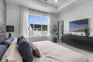 Bedroom with carpet flooring, ceiling fan, and a raised ceiling