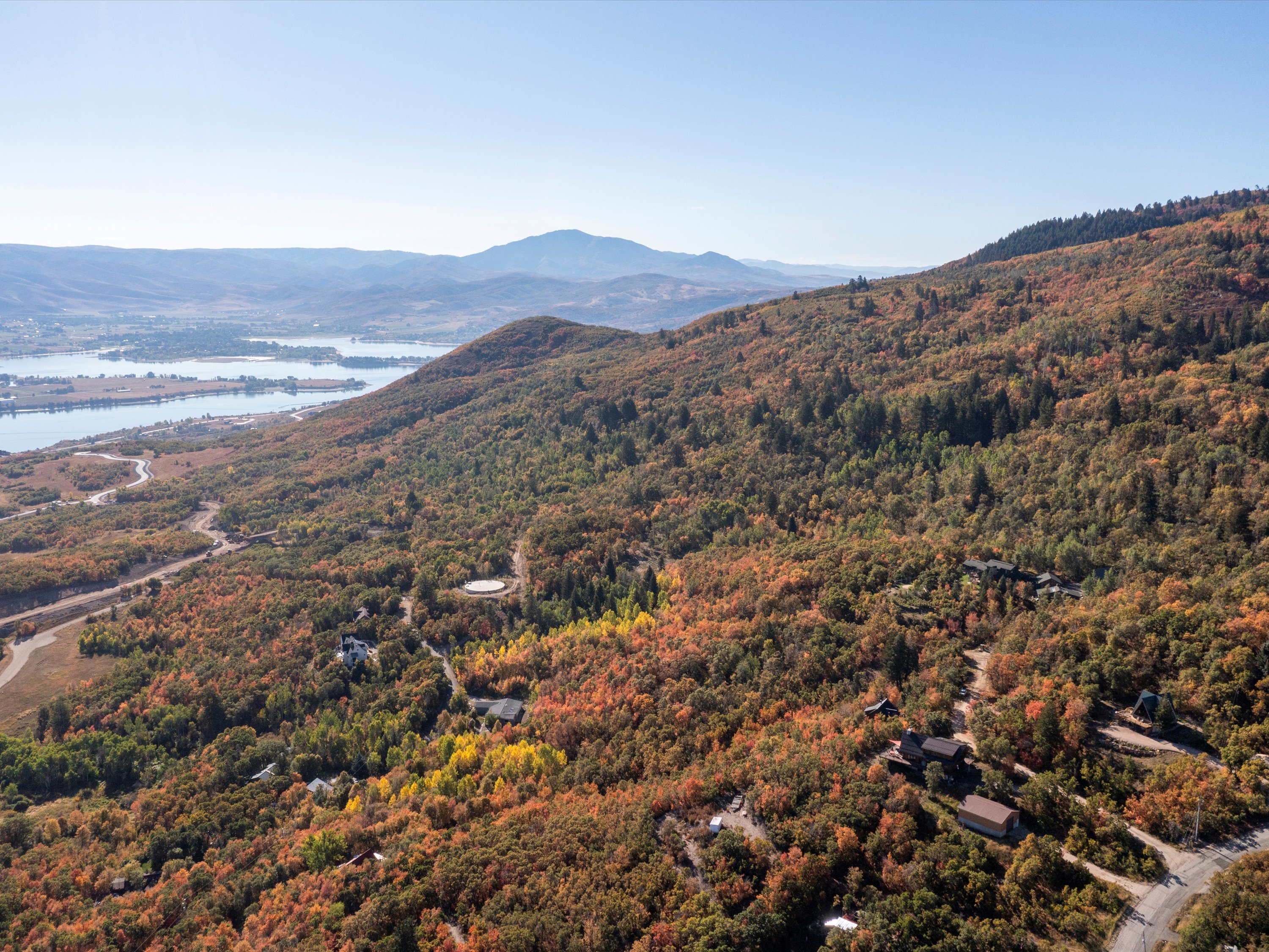 View of mountain backdrop featuring a nearby body of water and a heavily wooded area