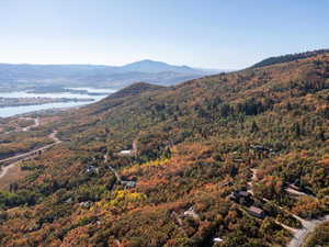 View of mountain backdrop featuring a nearby body of water and a heavily wooded area