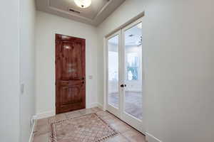 Foyer entrance with light tile patterned flooring, french doors, and inlaid floor details
