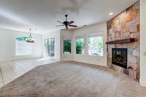 Unfurnished living room with light tile patterned floors, plenty of natural light, a ceiling fan, a fireplace, and recessed lighting