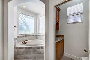 Bathroom featuring vanity, a bath, plenty of natural light, and light tile patterned floors