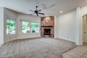 Unfurnished living room featuring light carpet, a ceiling fan, recessed lighting, a fireplace, and arched walkways