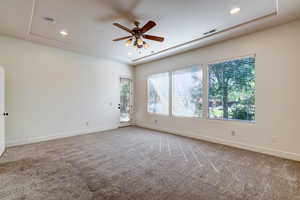 Empty room with light colored carpet, recessed lighting, a tray ceiling, and a ceiling fan