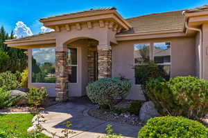 View of exterior entry with stucco siding, a tiled roof, and stone siding