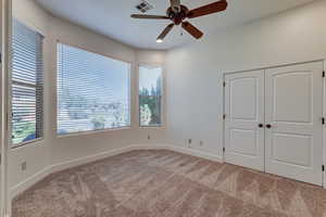 Unfurnished bedroom featuring light colored carpet, a closet, and ceiling fan