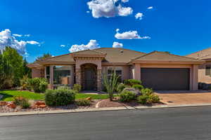 View of front of property with stucco siding, driveway, an attached garage, a tiled roof, and stone siding