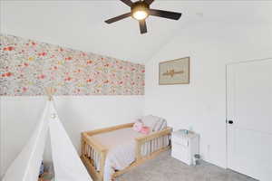 Bedroom featuring vaulted ceiling, carpet floors, a ceiling fan, and wainscoting