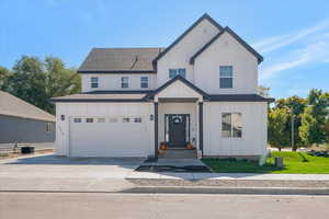 Modern inspired farmhouse with board and batten siding, roof with shingles, and driveway