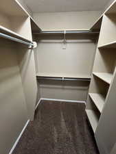 Walk in closet featuring dark carpet