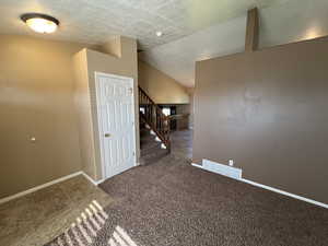 Carpeted spare room with a textured ceiling and stairs