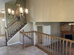 Stairs featuring a chandelier, a fireplace, and tile patterned floors
