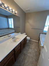 Bathroom with vanity, a garden tub, and a textured ceiling