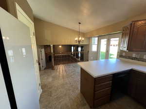 Kitchen featuring vaulted ceiling, light countertops, a peninsula, hanging light fixtures, and black dishwasher