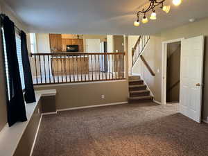 Unfurnished living room with stairs and dark colored carpet