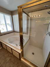 Bathroom featuring a stall shower, a whirlpool tub, and a textured ceiling