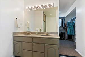 Bathroom featuring double vanity, a walk in closet, and a shower stall