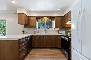 Kitchen with freestanding refrigerator, black electric range, a textured ceiling, light countertops, and a peninsula