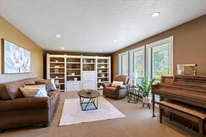 Living room with carpet floors, a textured ceiling, and recessed lighting