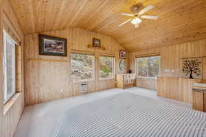 Unfurnished bedroom with vaulted ceiling, carpet flooring, wooden walls, and wooden ceiling